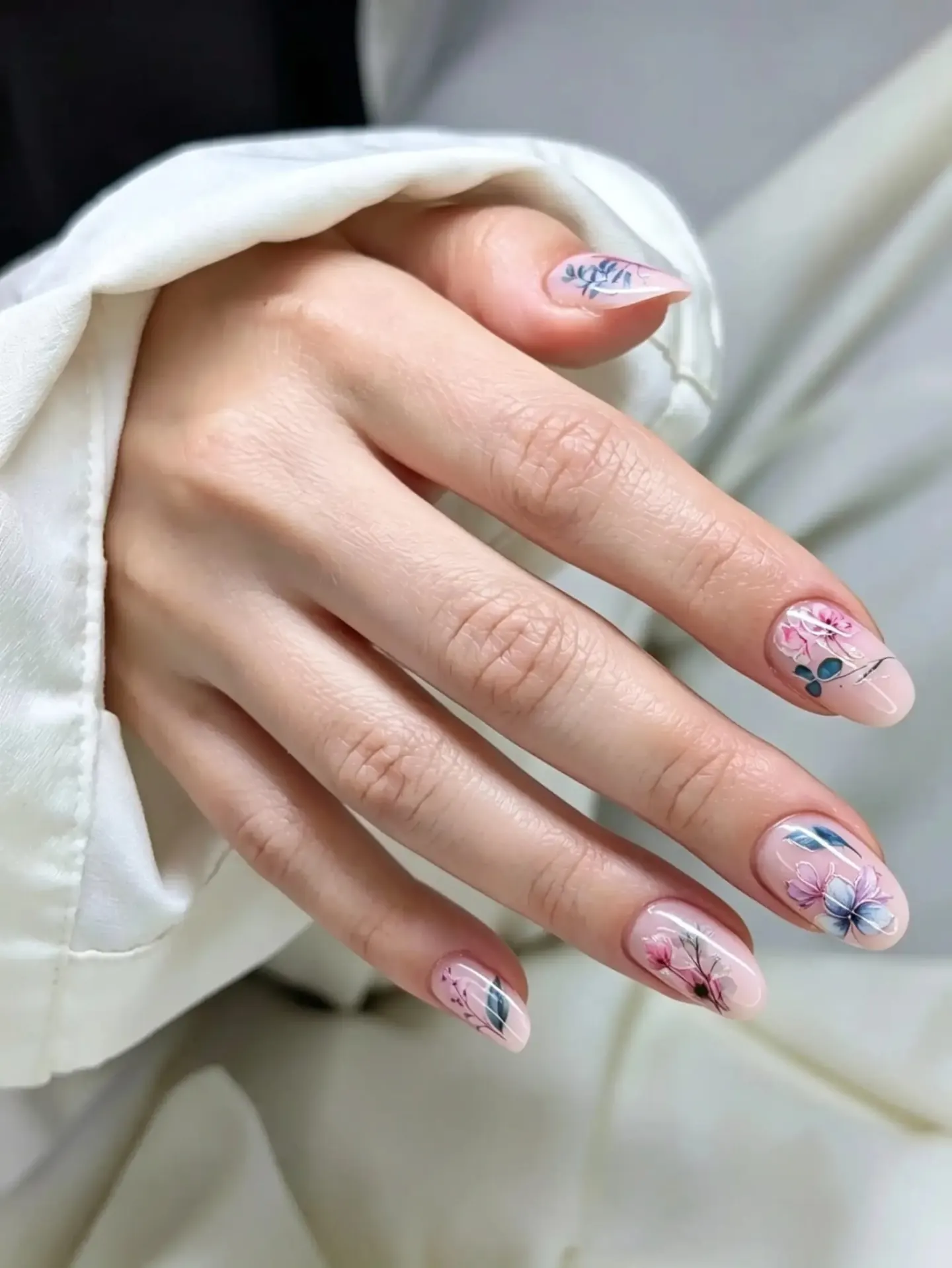 Mandelförmige Nägel in zartem Rosa mit Blüten und Blättern in Rosa und Blau