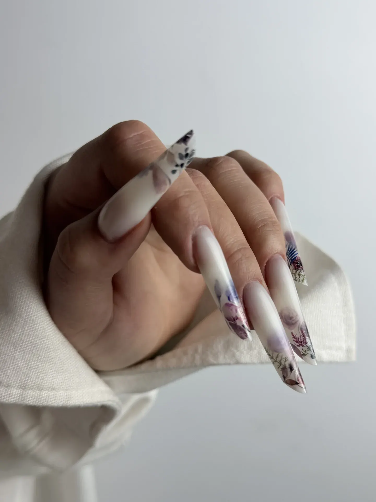 Lange mandelförmige Gelnägel mit von Hand gemalten Blättern und Blüten